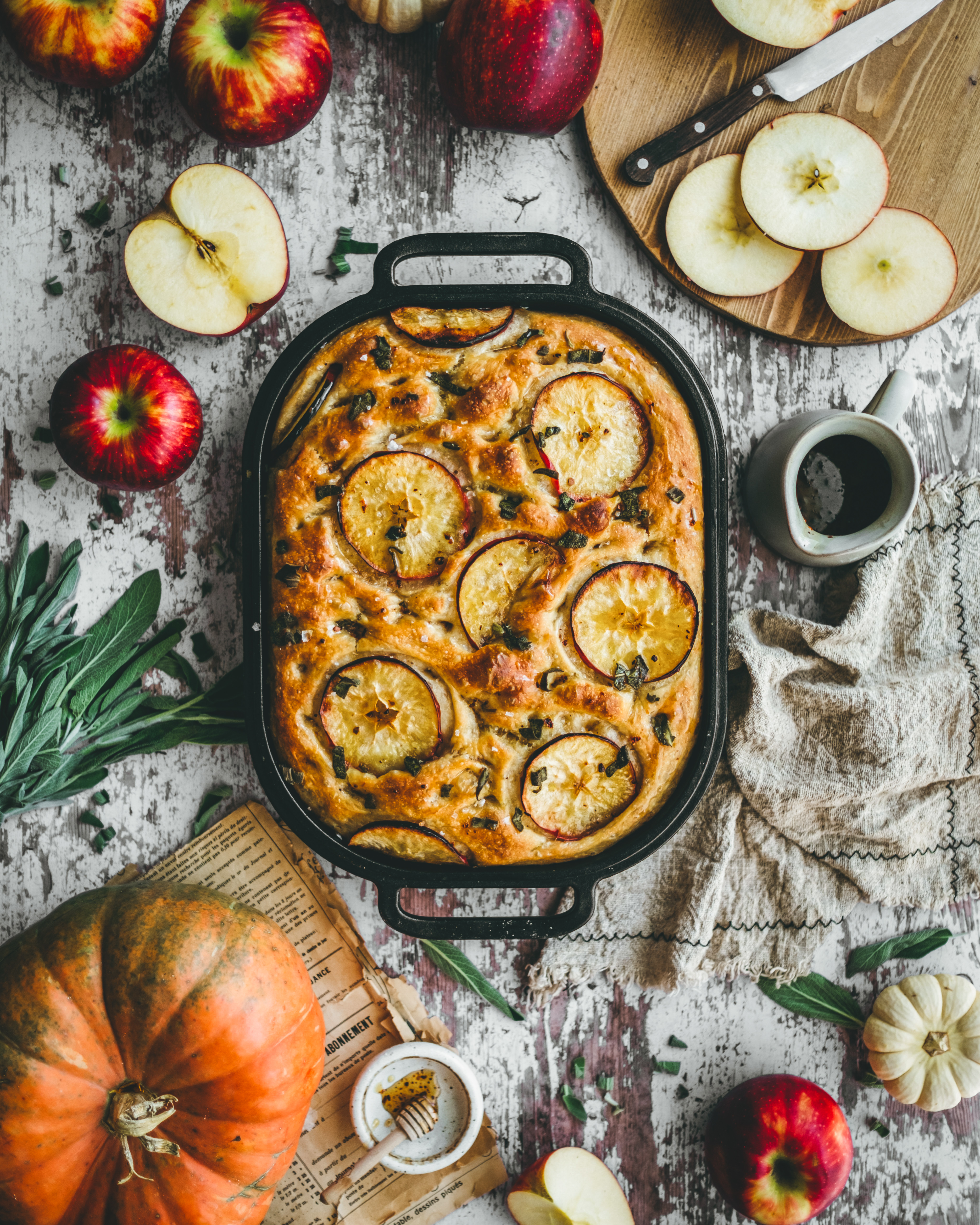 focaccia topped with apples, crispy sage, and hot honey, styled with apples and sage in a fall themed setting.