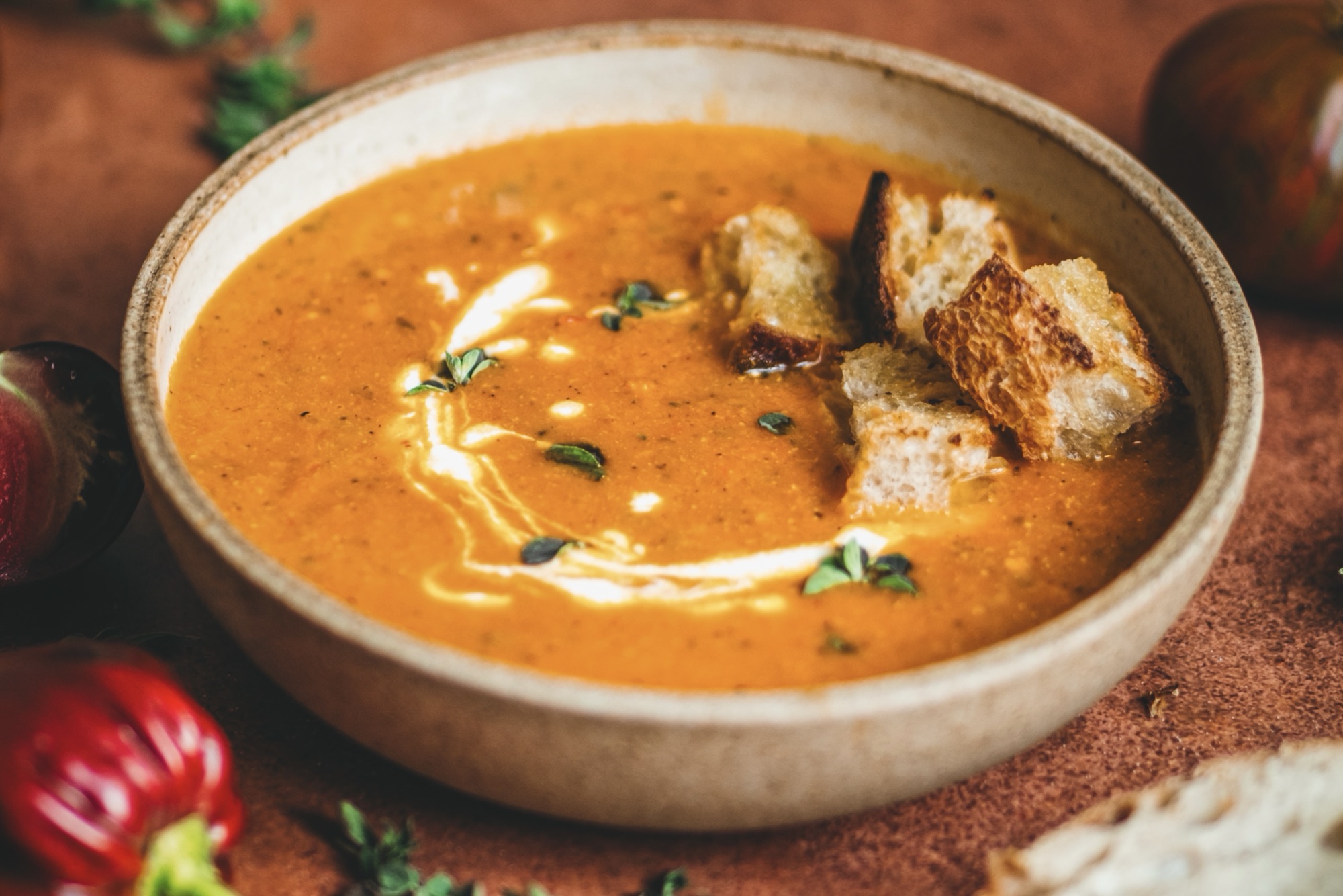 A bowl of roasted tomato soup, drizzled with creme fraiche and topped with sourdough croutons.