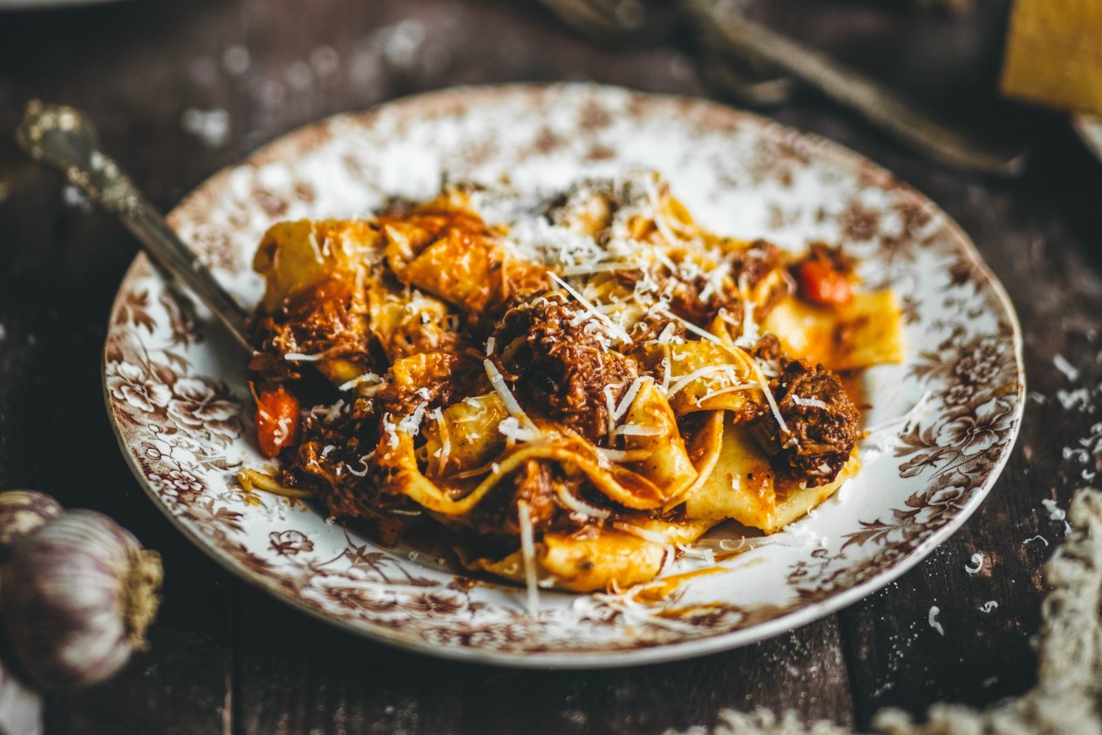 Slow cooked chuck ragù sauce served with papardelle, pasta, and styled on a rustic table.